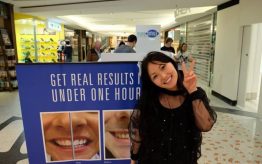 Teeth Whitening - Kouture Kitty posing next to before and after tarpaulin