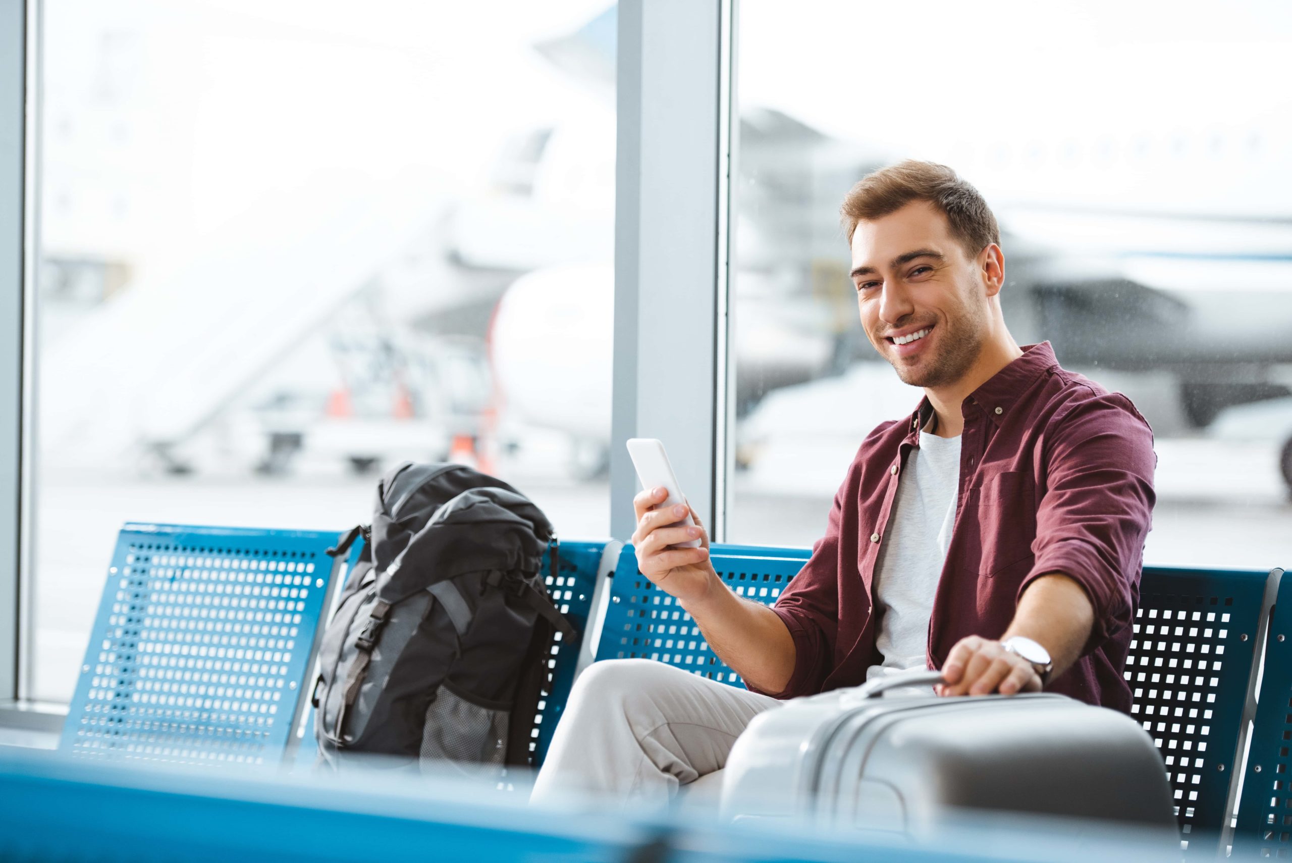 Cheerful man holding luggage in departure lounge