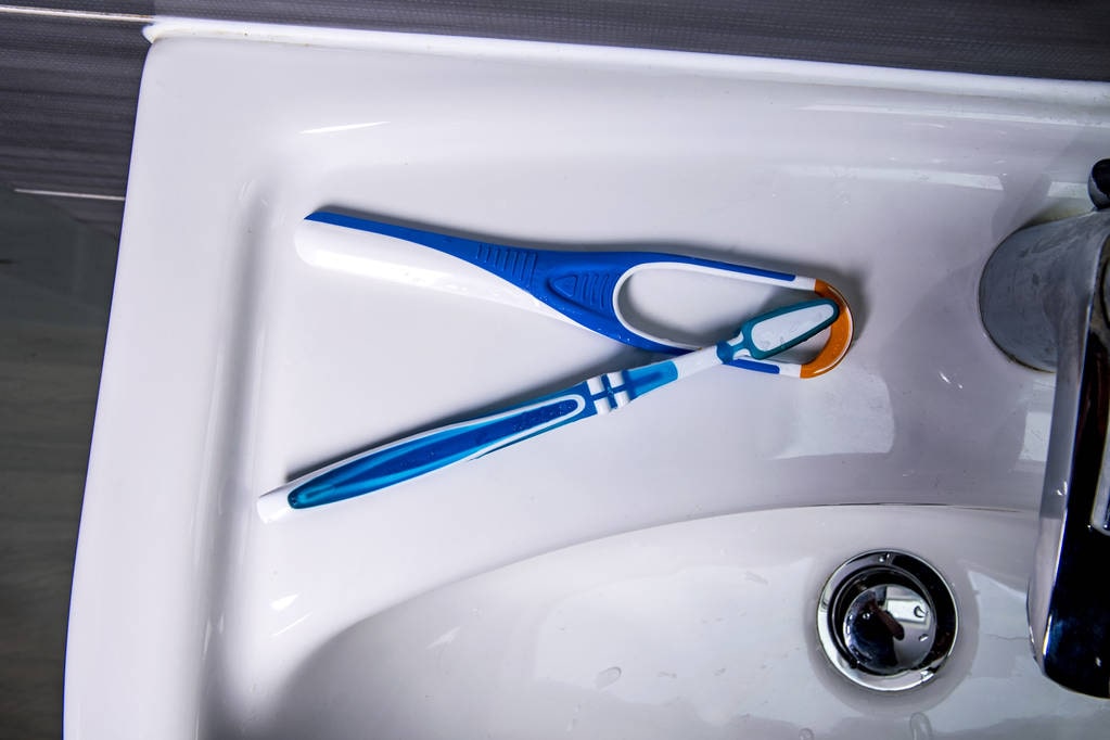Tongue scraper with toothbrush on the wash basin